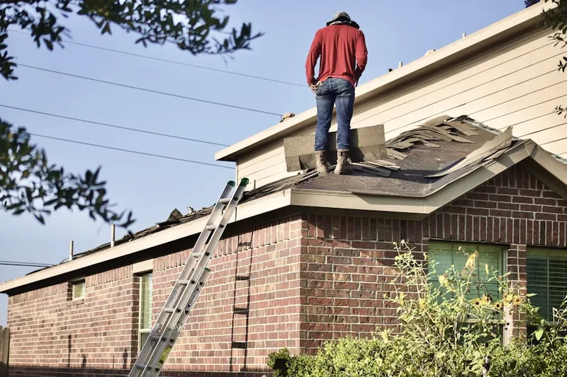 Professional roofer working on a residential roof in Larchmont Village Apartments West